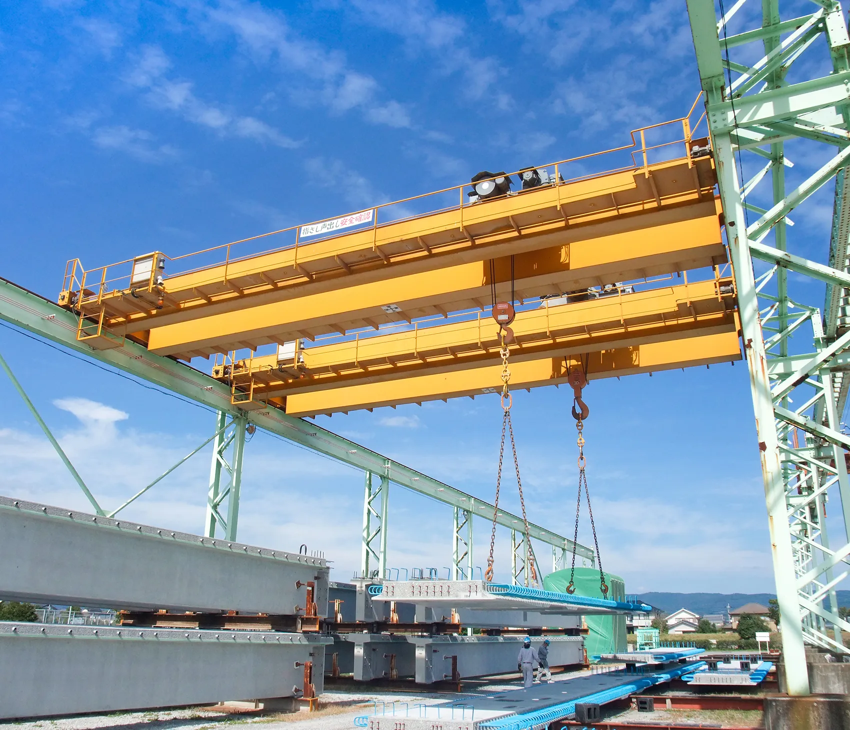 大型クレーンで橋桁を吊り上げる工場現場の様子