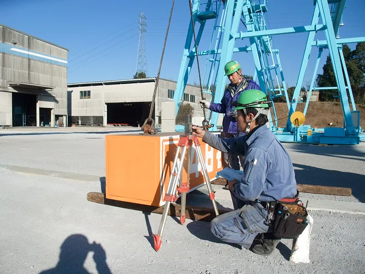 測量機器を使って屋外作業を行う作業員