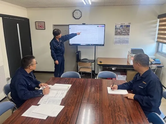 設計図と書類を確認しながら打ち合わせする3人の男性