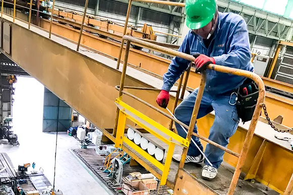 工場内クレーンの上で点検作業を行う作業員